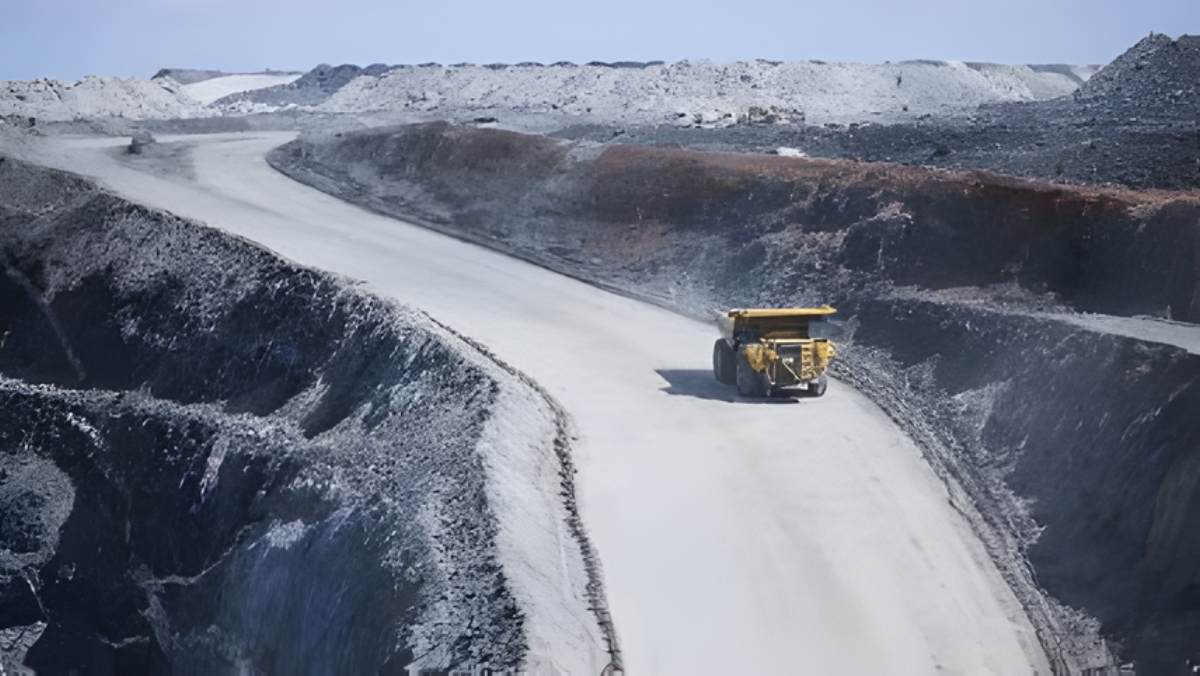 Yellow haul truck on a road in an open-cut mine with grey and white pit walls