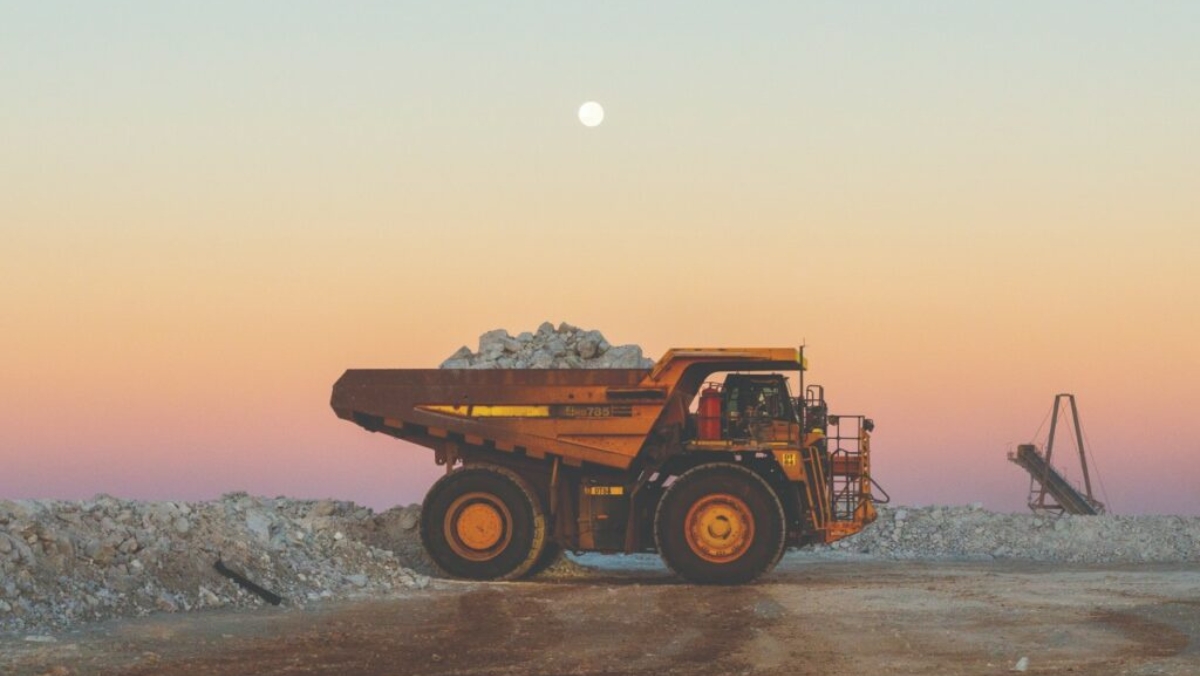Diesel haul truck carrying ore under a full moon at dusk